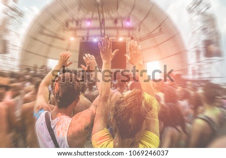 Happy friends having fun in color dust concert festival outdoor - Young people dancing at sunset in summer party - Main focus on heads - Youth and friendship concept with multi colored powder game