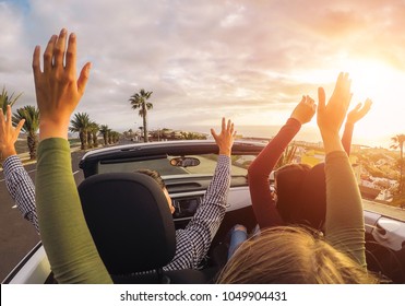Happy friends having fun in convertible car at sunset in vacation - Young people making party and dancing in a cabrio auto during their road trip - Friendship, travel, youth lifestyle concept