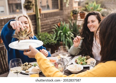 Happy Friends Having Fun Drinking And Eating Vegan Food At Patio Restaurant - Focus On Hand Holding Artichoke