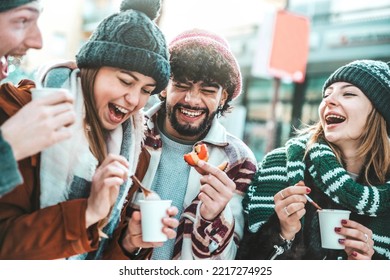 Happy friends having fun drinking mulled wine and hot chocolate at Christmas Market - Cheerful young people enjoying winter holidays on weekend vacation - Tourism lifestyle and friendship concept - Powered by Shutterstock