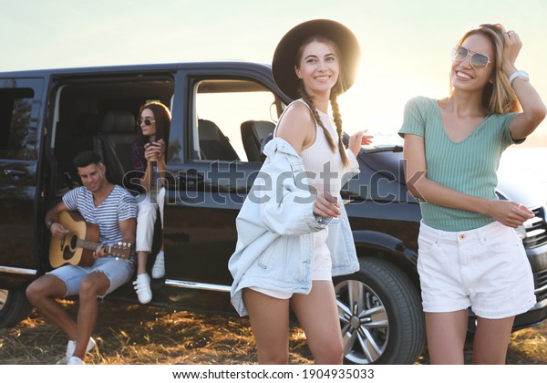 Happy\
friends having fun near car outdoors. Summer\
trip