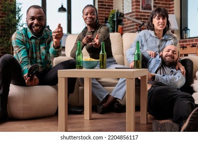 Happy Friends Having Fun Playing Video Games Strategy At House Party With Bottles Of Beer And Snacks. Group Of Friends Celebrating Hangout Reunion While They Play Game On Tv Console.