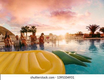 Happy friends having fun in pool party at sunset - Rich people drinking and laughing in exclusive tropical vacation - Holiday and friendship concept - Main focus on center guys - Powered by Shutterstock