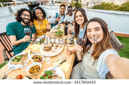 Happy friends having fun at rooftop dinner party - Group of young people taking selfie photo at outdoors dining table - Life style concept with guys and girls eating food and drinking wine together