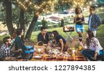 Happy friends having fun at vineyard after sunset - Young people millennial camping at open air picnic under bulb lights - Youth friendship concept with guys and girls drinking wine at barbecue party