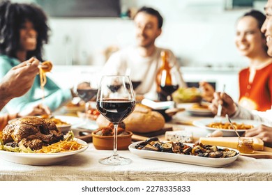 Happy friends having pasta dinner party at home - Multiracial people drinking red wine at lunch break - Food and beverage concept with guys and girls dining together - Powered by Shutterstock