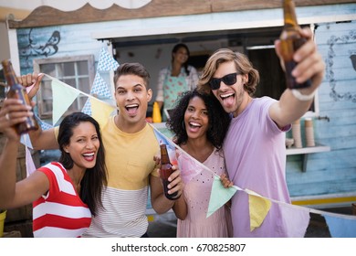 Happy Friends Holding Beer Bottles Near Food Truck