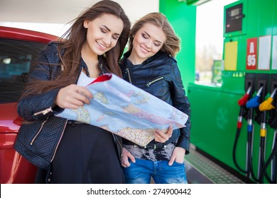 Happy Friends Holding Map In Gas Station. Holiday Trip Of Friends