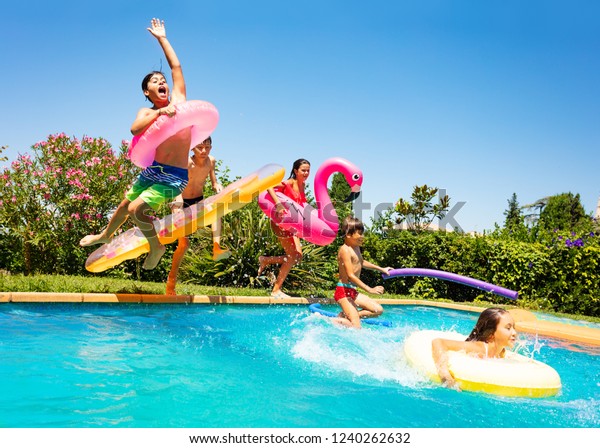 Happy friends\
jumping in pool on the\
vacations