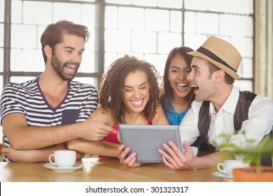 Happy Friends Laughing While Looking At Tablet At Coffee Shop