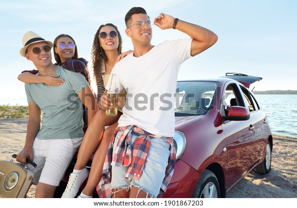 Happy friends near
car on beach. Summer trip