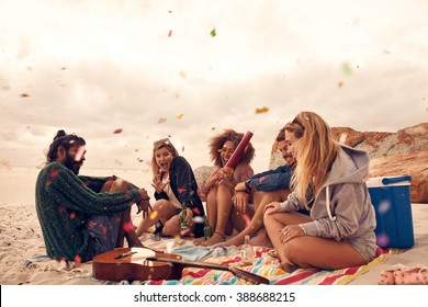Happy friends partying on the beach with drinks and confetti. Happy young people having fun at beach party, celebrating with confetti. - Shutterstock ID 388688215