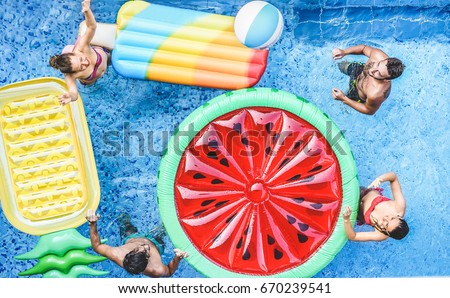 Happy friends playing with ball inside swimming pool - Young people having fun on summer holidays vacation - Travel,holidays,youth,friendship and tropical concept - Seasonal color tones filter