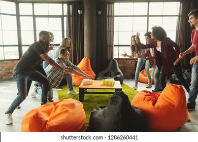 Happy friends playing beer pong game on party in loft - Powered by Shutterstock