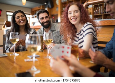 Happy friends playing cards while having glass of beer in bar - Powered by Shutterstock