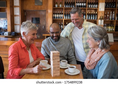 Happy friends playing jenga game while having cup of coffee in bar - Powered by Shutterstock