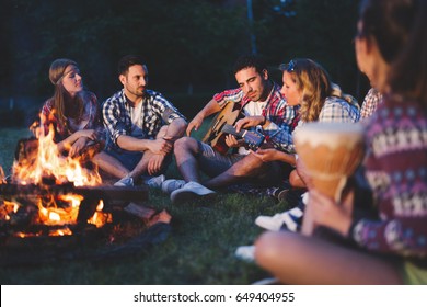 Glückliche Freunde spielen Musik und genießen das Feuerfeuer