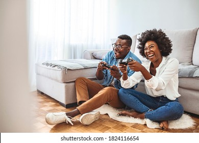 Happy friends playing video games with virtual reality glasses - Young people having fun with new technology console online. Young African American Couple Playing On Game Console With Joysticks - Shutterstock ID 1824116654