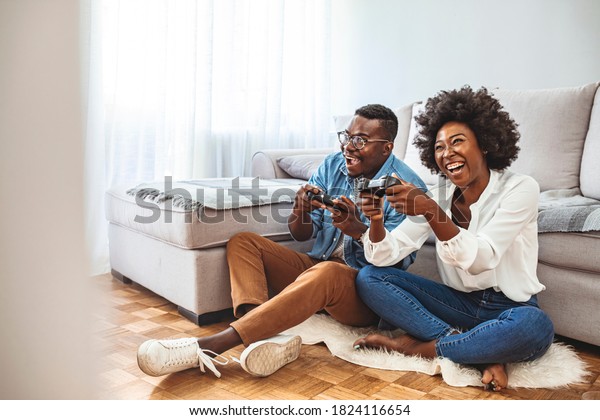 Happy friends playing video games with virtual\
reality glasses - Young people having fun with new technology\
console online. Young African American Couple Playing On Game\
Console With Joysticks