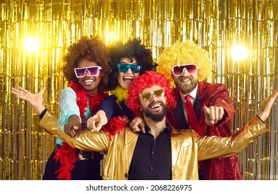 Happy Friends Point Fingers At Camera Inviting You To Join 70s Style Fancy Dress Fun Groovy Disco Party. Funny Photobooth Group Portrait Of Excited Young People At New Year Eve Or Birthday Celebration