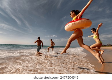 Happy friends runs and jumps with inflatable donuts to sea beach - Powered by Shutterstock