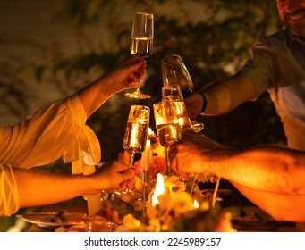 HAppy friends saying cheers and showing their champagne glasses full of sparkling wine to each other whilst enjoying an outdoor wedding party on a backyard restaurant at sunset - Powered by Shutterstock