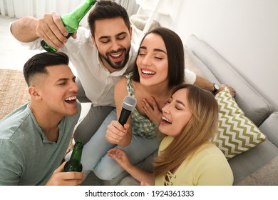 Happy friends singing karaoke together at home