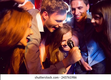 Happy friends singing karaoke together at the nightclub - Powered by Shutterstock
