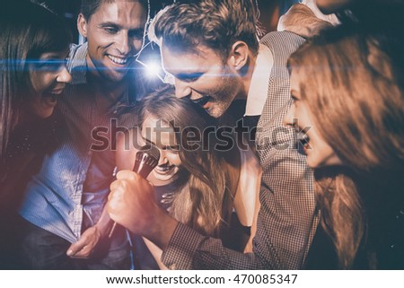 Happy friends singing karaoke together at the nightclub