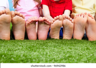 Happy friends sitting on the grass barefoot