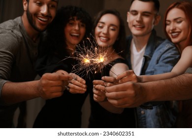 Happy friends with sparklers celebrating birthday indoors, focus on hands - Powered by Shutterstock