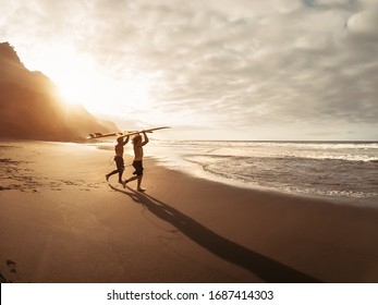 Happy friends surfing together on tropical ocean - Sporty people having fun during vacation surf day - Extreme sport lifestyle concept - Powered by Shutterstock