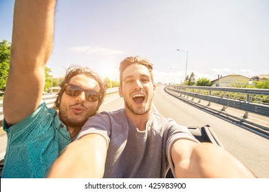 Happy friends taking a selfie at car trip - Two caucasian tourist travelling around the world