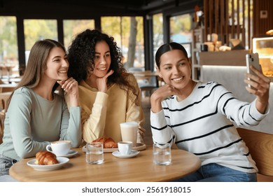 Happy friends taking selfie during coffee meeting in cafe - Powered by Shutterstock