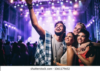Happy friends taking selfie at music festival - Powered by Shutterstock