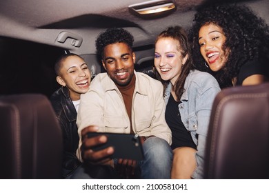 Happy Friends Taking A Selfie Together Inside A Car At Night. Group Of Young Friends Smiling Cheerfully While Posing For A Group Photo. Carefree Friends Taking A Ride Home After A Party.