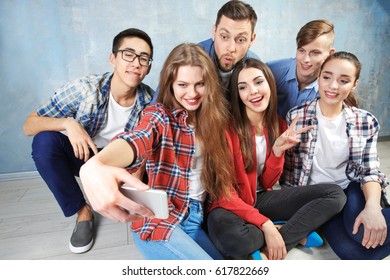 Happy friends taking selfie while sitting on floor indoors - Shutterstock ID 617822669