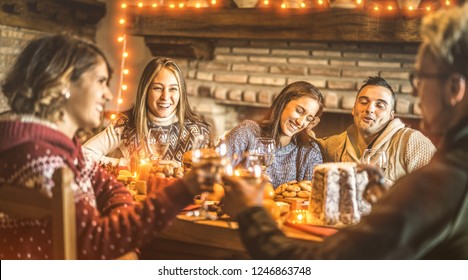 Happy Friends Tasting Christmas Sweet Food At Home Fun Party - New Year's Eve Mood With White Wine Glasses Toast - Winter Holiday Concept With Young People Eating Together - Bulb Lights Warm Filter