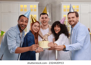 Happy friends with tasty cake and sparklers celebrating birthday in kitchen - Powered by Shutterstock