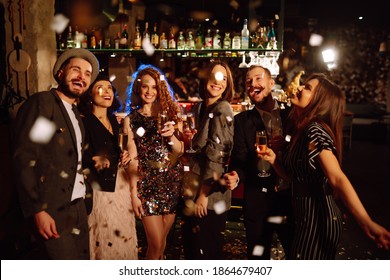 Happy friends throwing confetti and jumping while enjoying party. Group of  young people celebrating together winter holiday. Confetti is fun. Party, celebration, drink, birthday concept. - Powered by Shutterstock