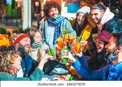 Happy Friends Toasting Fancy Drinks At Night Bar With Open Mask - New Normal Lifestyle Concept With Millennial People Having Fun Together On Winter Clothes At Apres Ski - Focus On Bearded Guy Face