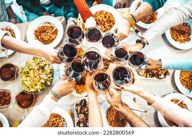 Happy friends toasting red wine glasses at dinner party - Group of people having lunch break at bar restaurant - Life style concept with guys and girls hanging out together - Food and beverage  - Powered by Shutterstock