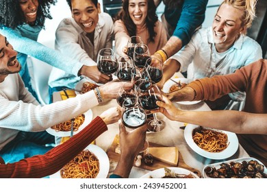 Happy friends toasting red wine glasses at dinner party - Winery life style concept with guys and girls drinking wineglass together - Powered by Shutterstock