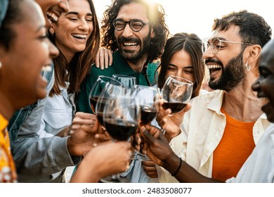 Happy friends toasting red wine glasses outside - Group of young people having bbq dinner party in backyard house - Winery and bbq dining concept with guys and girls cheering alcohol together - Powered by Shutterstock