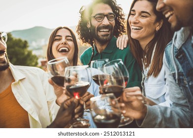 Happy friends toasting red wine glasses outside - Group of young people having bbq dinner party in backyard house - Winery and bbq dining concept with guys and girls cheering alcohol together - Powered by Shutterstock