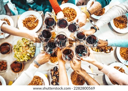 Happy friends toasting red wine glasses at dinner party - Group of people having lunch break at bar restaurant - Life style concept with guys and girls hanging out together - Food and beverage 