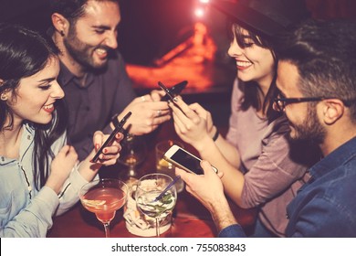 Happy friends using mobile phone and having fun with cocktails in a jazz bar - Young people addicted to new smartphone technology - Concept of youth, cellphone and lifestyle - Focus on right male hand - Powered by Shutterstock