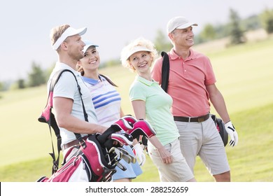 Happy friends walking at golf course