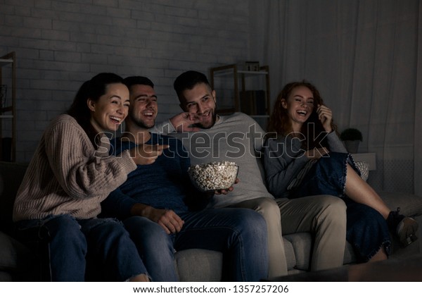 Happy friends watching comedy film and laughing,\
relaxing at home together