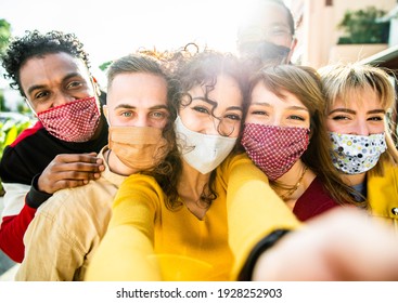 Happy friends wearing face masks taking a selfie outdoor - New normal friendship concept with young people having fun in the city - Main focus on central girl - Powered by Shutterstock